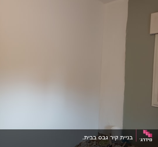 קיר גבס עם ערימת פסולת בנייה ודלי